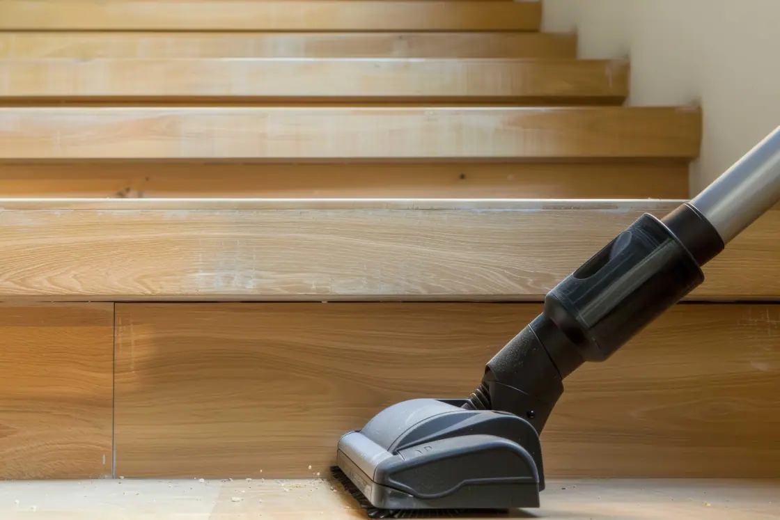 Staubsaugerdüse reinigt eine helle Holztreppe